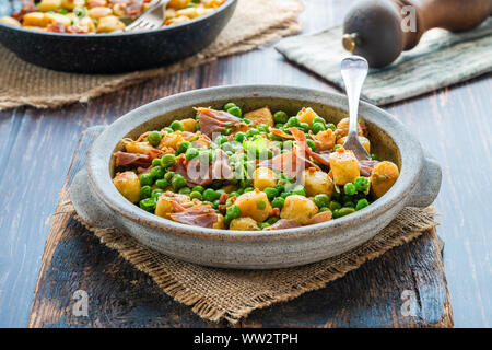 Gnocchi mit grünen Erbsen, Pesto, Schinken und Chorizo in eine Schüssel geben. Stockfoto