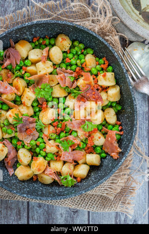 Gnocchi mit grünen Erbsen, Pesto, Schinken und Chorizo in Pfanne - Ansicht von oben Stockfoto