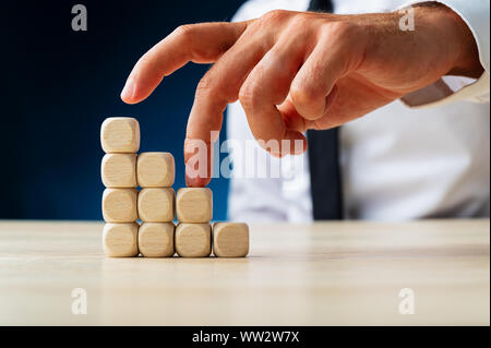 Geschäftsmann seinen Finger nach oben, eine Treppe aus Holz Würfel in einem konzeptionellen Bild. Stockfoto