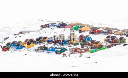 Mehrere bunte Inuit Häuser und Bungalows auf dem Hügel mit Schnee bedeckt, Aasiaat Stadt, Grönland Stockfoto