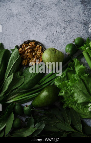 Frisches Grün essen, Vielfalt an Gemüse, grünen und Früchte mit Walnüssen. Gesunde Ernährung Konzept. Flatlay Zusammensetzung auf die texturierte konkreten Hintergrund w Stockfoto