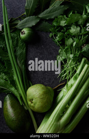 Frisches Grün essen, Vielfalt an Gemüse, grünen und Früchte auf dunklen konkreten Hintergrund. Gesunde Ernährung Konzept. Monochromatische Idee. Compositio Flatlay Stockfoto