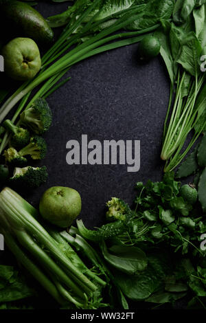 Frisches Grün essen, Vielfalt an Gemüse, grünen und Früchte auf dunklen konkreten Hintergrund. Gesunde Ernährung Konzept. Monochromatische Idee. Compositio Flatlay Stockfoto