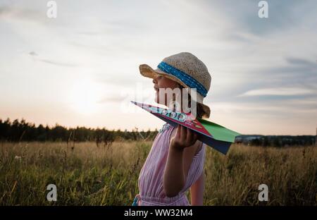 Nahaufnahme Portrait eines Mädchen spielen mit Papier Flugzeuge in einer Wiese Stockfoto