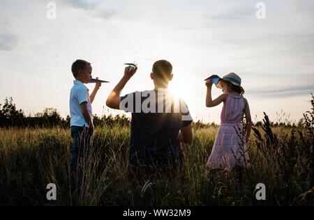 Vater mit seinem Sohn und Tochter auf einer Wiese bei Sonnenuntergang Stockfoto