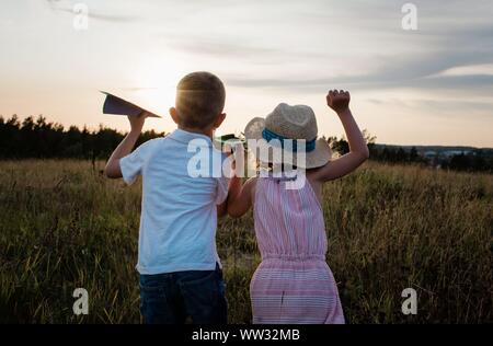 Bruder und Schwester schaut in die Ferne spielen bei Sonnenuntergang Stockfoto