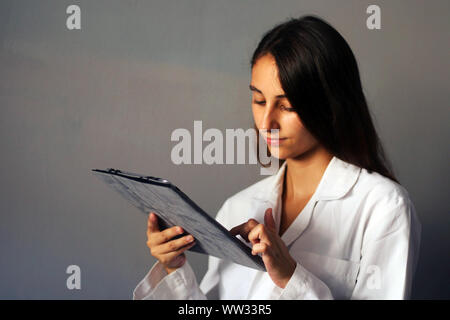 Medizin Konzept: junge Ärztin auf grauem Hintergrund mit einem digitalen Tablet. Healthcare Technologie. Stockfoto