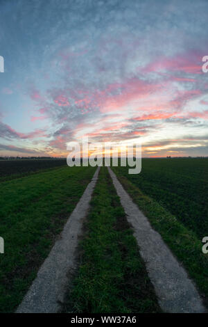 Landstraße in den Niederlanden unter einem bunten Himmel Stockfoto