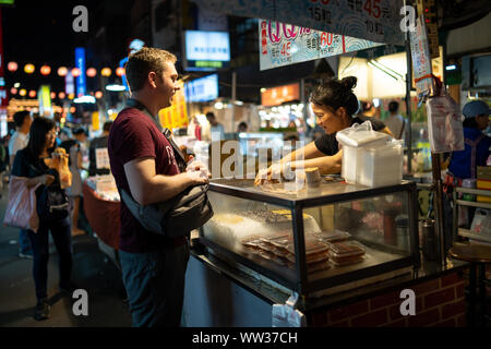 Taipei, Taiwan: Europäische Touristen kaufen traditionelle taiwanesische Mochi an Street Food Verkäufer Raohe Nachtmarkt Stockfoto