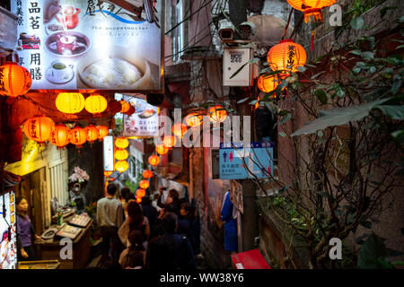 Schmale Jiufen Old Street mit Touristen wandern und Shopping. Traditionelle Chinesische Laternen entlang der schmalen Straße hängen. Stockfoto