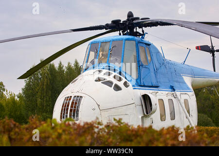 Kleine weiße Hubschrauber mit einem blauen Streifen auf dem grünen Rasen. Stockfoto