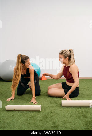 Zwei junge Frauen Lächeln während des Trainings und Strecken. Konzept der Muskel Gesundheit und Entspannung. Bild vertikal Stockfoto