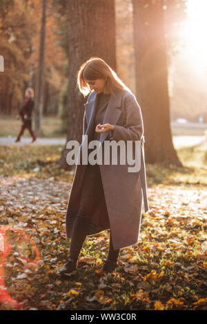 Hübsches Mädchen Wandern im Herbst Park. Schönen Herbst sonniges Wetter. Junge Frau genießen. Frauen Mode. Herbstferien. Menschen, Herbst und Leben Stockfoto