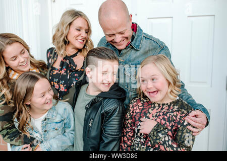 Familie umarmen und lächelnd an Mädchen mit Down-syndrom Stockfoto