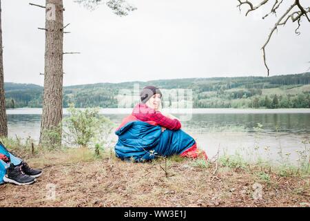 Frau lachend, während in einem Schlafsack Camping in Norwegen sitzen Stockfoto