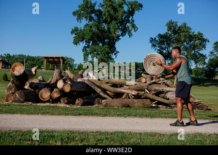 Ein athletischer Mann bereitet eine Rolle von schweren firehose in einem Park zu werfen Stockfoto