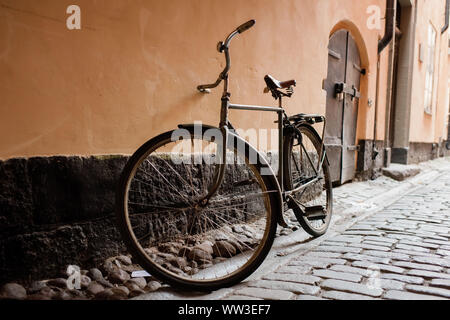 Alte europäische Fahrrad gegen eine Wand auf einer gepflasterten Straße Stockfoto
