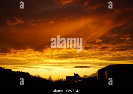 Brennender Himmel über der Stadt, Wolken wie Feuer bei Sonnenuntergang Stockfoto
