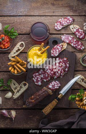 Räucherwurst und knuspriges Brot mit Rotwein, Ansicht von oben. Stockfoto