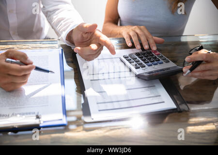 Mitte von zwei Arbeitnehmer Berechnung Berichts, während sich die Zusammenarbeit in Office Stockfoto