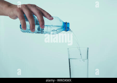 Gießen Glas Wasser aus einer Kunststoffflasche Stockfoto