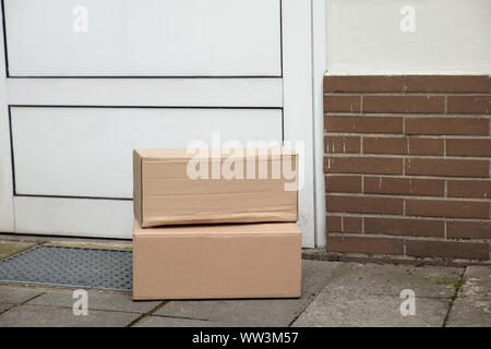 Stapel von braunen Kartons geliefert vor der Haustür Stockfoto