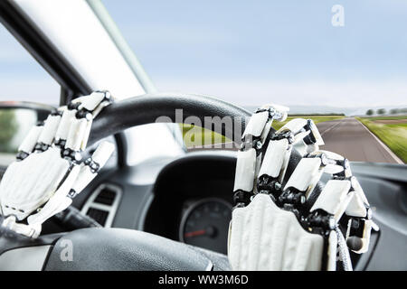 Nahaufnahme der Robotic Hand auf's Auto Lenkrad Stockfoto