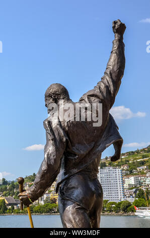 Montreux, Schweiz - 26. Juli 2019: berühmte Statue von Freddie Mercury, der Sänger der berühmten Band Queen. Stadt durch den Genfer See im Hintergrund. Beliebte touristische Sehenswürdigkeit. Freddy Mercury, Farrokh Bulsara. Stockfoto