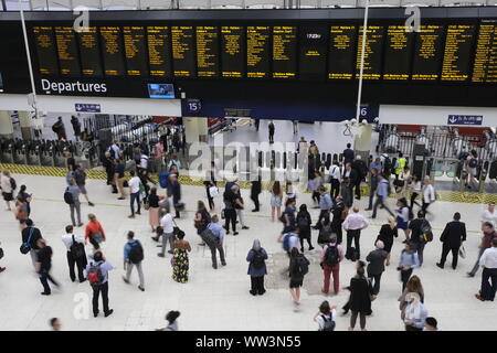August 2019. Pendler an den zentralen Eingangsbereich von London Waterloo Bahnhof vorbei gehen und Prüfen der grossen Anzeigetafel, London, UK Stockfoto