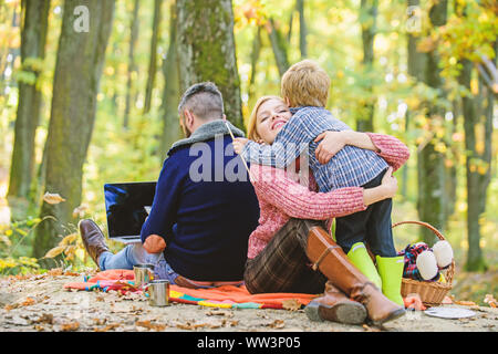 Glücklich, der Sohn mit den Eltern im Herbst Wald entspannen. Mutter, Vater lieben ihren kleinen Jungen Kind. Herbst Wetter. Wein oder Kaffee trinken. Frühling Stimmung. Happy Family Day. Familie Picknick. Ostern feiern. Stockfoto