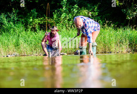 Männer sitzen am Flußufer mit Angelausrüstung. Wilderer angeln. Die wilderei Kriminalität und Lizenz. Schwarzmarkt Kaviar. Die illegale Jagd Kaviar. Auszüge Eier vom Stör gefangen. Trap für Fische. Stockfoto