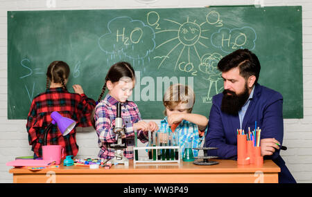 Schule Chemie Experiment. Erklären der Chemie zu Kindern. Faszinierende Chemie Lektion. Man bärtige Lehrer und Schüler mit Reagenzgläsern im Klassenzimmer. Beobachten Sie die Reaktion. Wissenschaft ist immer die Lösung. Stockfoto