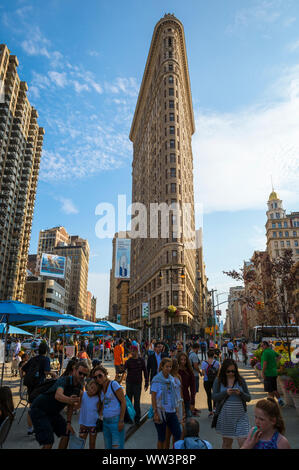 NEW YORK - 11. AUGUST 2017: Besucher nehmen selfies vor dem Flatiron Building, einer der ersten und berühmtesten Wolkenkratzer der Stadt. Stockfoto