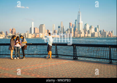 HOBOKEN, NJ, USA - 15. AUGUST 2017: Besucher gehen die Uferpromenade Fotos vor der Skyline von New York City am Hudson River. Stockfoto