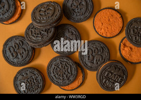 Halloween Schokolade Cookies mit einer orange Creme gefüllt Zentrum einige ausgesetzt Schließen bis auf einen orangen Hintergrund Stockfoto
