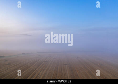 Niedriger Höhe drone Schießen über misty Ernte bei Sonnenaufgang in Shropshire, Großbritannien Stockfoto