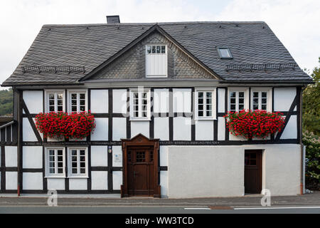 Architektur der typischen Fachwerkhäuser Vakwerk in das Spa Village von Grafschaft im Sauerland in Deutschland mit roten Blumen Dekoration Stockfoto