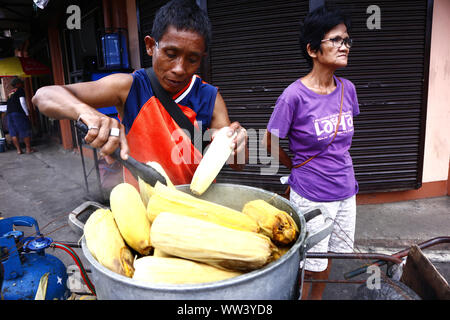 ANTIPOLO CITY, Philippinen - 9. SEPTEMBER 2019: Straßenhändler verkauft frisch gekochten Mais auf ein Cob auf seinem Essen Warenkorb. Stockfoto