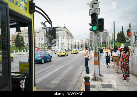 Athen Griechenland - 15. JULI 2019; Frau am Fußgängerüberweg Gespräch am Handy während Fahrzeuge und ein Bus Pass warten Stockfoto