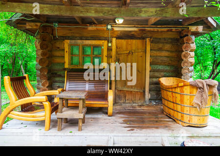 Die Veranda mit einem kleinen Badehaus auf der Veranda, von denen gibt es Bänke und eine große alte Bad. Erholung und Gesundheit in der Natur. Stockfoto