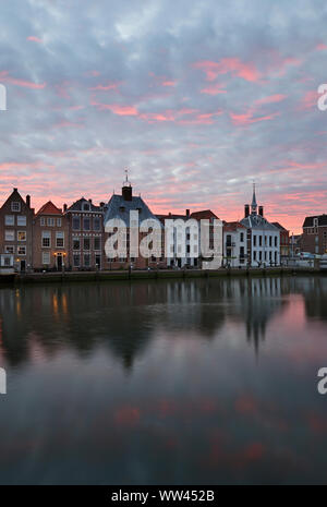 Die historische Innenstadt von Maassluis, Niederlande am Hafen entlang. Sunrise leuchtet hinter antiken alten Gebäuden. Sonnenuntergang hinter der alten Kirche. Malerische Landschaft Stockfoto