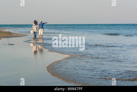 Liebende Flitterwochen Paar, die im Sommer am tropischen Strand spazieren gehen, reisen an die Küste eines Meeres Stockfoto