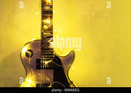 E-Gitarre mit beleuchtete Girlande auf dunklem Hintergrund. Neue Jahr Geschenk in Form von teuren E-Gitarren. Geschenk für den Musiker zu Weihnachten. Stockfoto