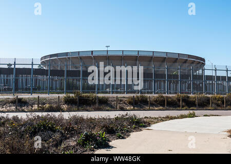 Grenzzaun zwischen San Diego und Tijuana, Mexiko, mit einer Stierkampfarena auf die Mexiko Seite. Stockfoto