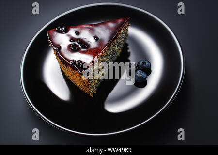 Kuchen mit Früchten, Chia Getreide und Nüsse in eine Platte auf schwarzem Hintergrund Stockfoto
