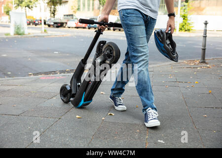 Man E-Scooter zu Fuß auf der Straße arbeiten Stockfoto