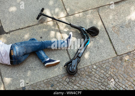 Unbewussten Mann liegen auf konkrete Straße nach Unfall mit einem Elektroroller Stockfoto