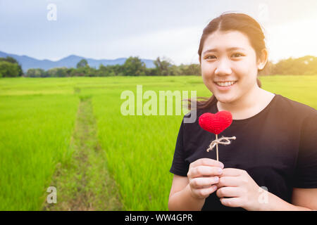 Asiatische cute Teen Girl plus Größe mit roten Herzen liebe grüne Natur Hintergrund Platz für Text Stockfoto