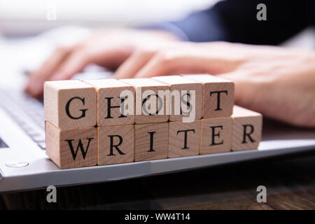 Ghostwriter Holzklotz auf dem Computer Tastatur, während jemand eingeben Stockfoto