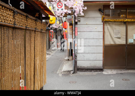 Ein japanischer Mann nähert sich in engen Gasse Straße von izakayas und winzige Diners eng zusammen Omoide Yokocho in Shinjuku, Tokyo, Japan genannt. Stockfoto